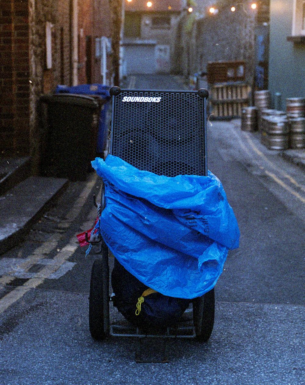 A speaker on a trolly covered in a blue waterproof tarpe